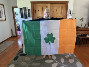 Woman holding an Irish tricolor flag with a green shamrock.