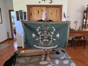 Woman holding a green Woodworth family crest flag with a Celtic knot border.