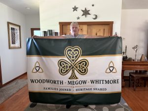 Man holding the Woodworth, Megow and Whitmore family flag with a Celtic shamrock.